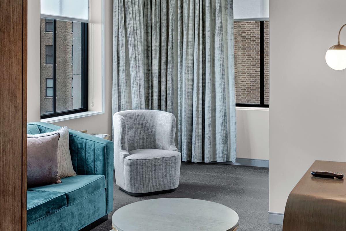 A modern living room with a teal sofa, a grey armchair, and a round coffee table.