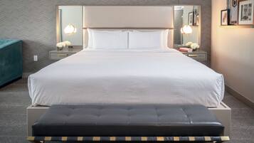 A neatly arranged hotel room with a large bed, bedside tables with lamps, a bench, and a herringbone-patterned wall.