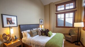 A neatly arranged bedroom with a bed, bedside table, lamp, and a chair.
