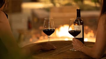 Two people sitting at a wooden table with a bottle of wine and two wine glasses.