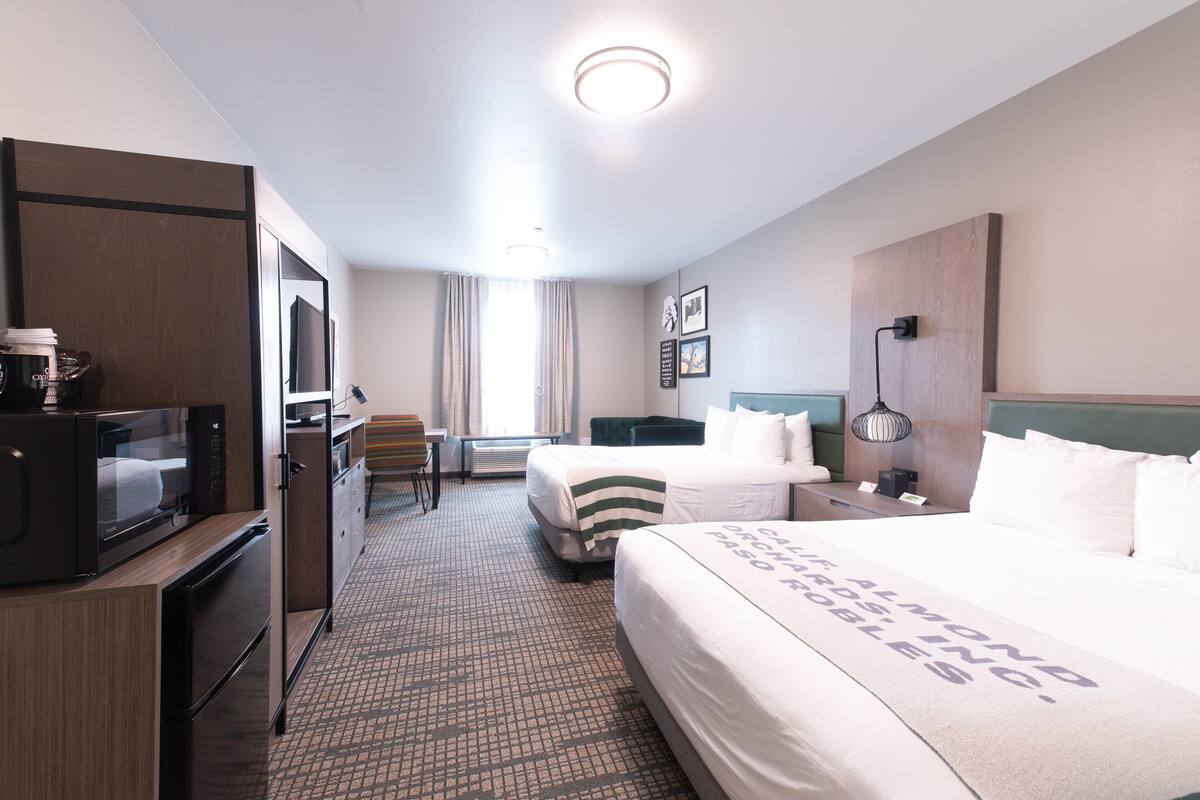A hotel room with a bed, a desk, a microwave, and a refrigerator.