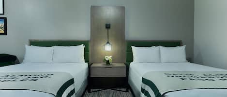 Une chambre d’hôtel avec deux lits, une table de chevet avec une lampe et une couvre-lit à rayures vertes et blanches.