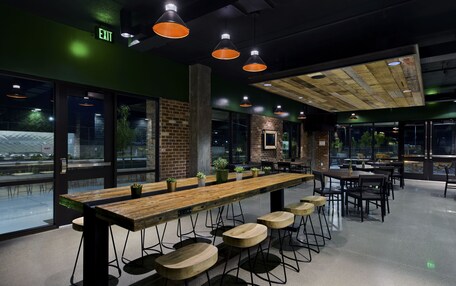 A modern bar area with a long wooden counter, bar stools, and pendant lighting.
