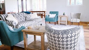 Een woonkamer met een bank, stoelen, een salontafel en een eethoek.