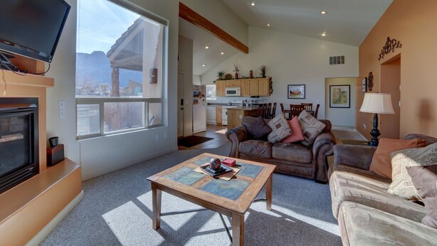 A spacious living room with a fireplace, a television, and a large window. - Mountain Views In the heart Of Canyon Country; Adventure base for your visit! (Moab)
