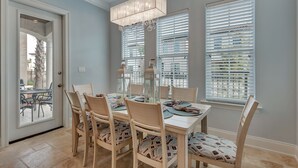 A dining area with a table set for four, surrounded by chairs with patterned cushions.