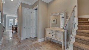 A hallway with a staircase, a door, and a vanity with drawers.