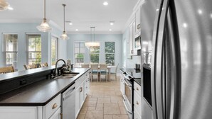 A modern kitchen with a large island, stainless steel appliances, and pendant lighting.
