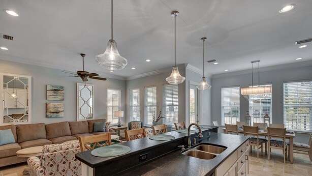A spacious kitchen with a central island, pendant lighting, and a ceiling fan.