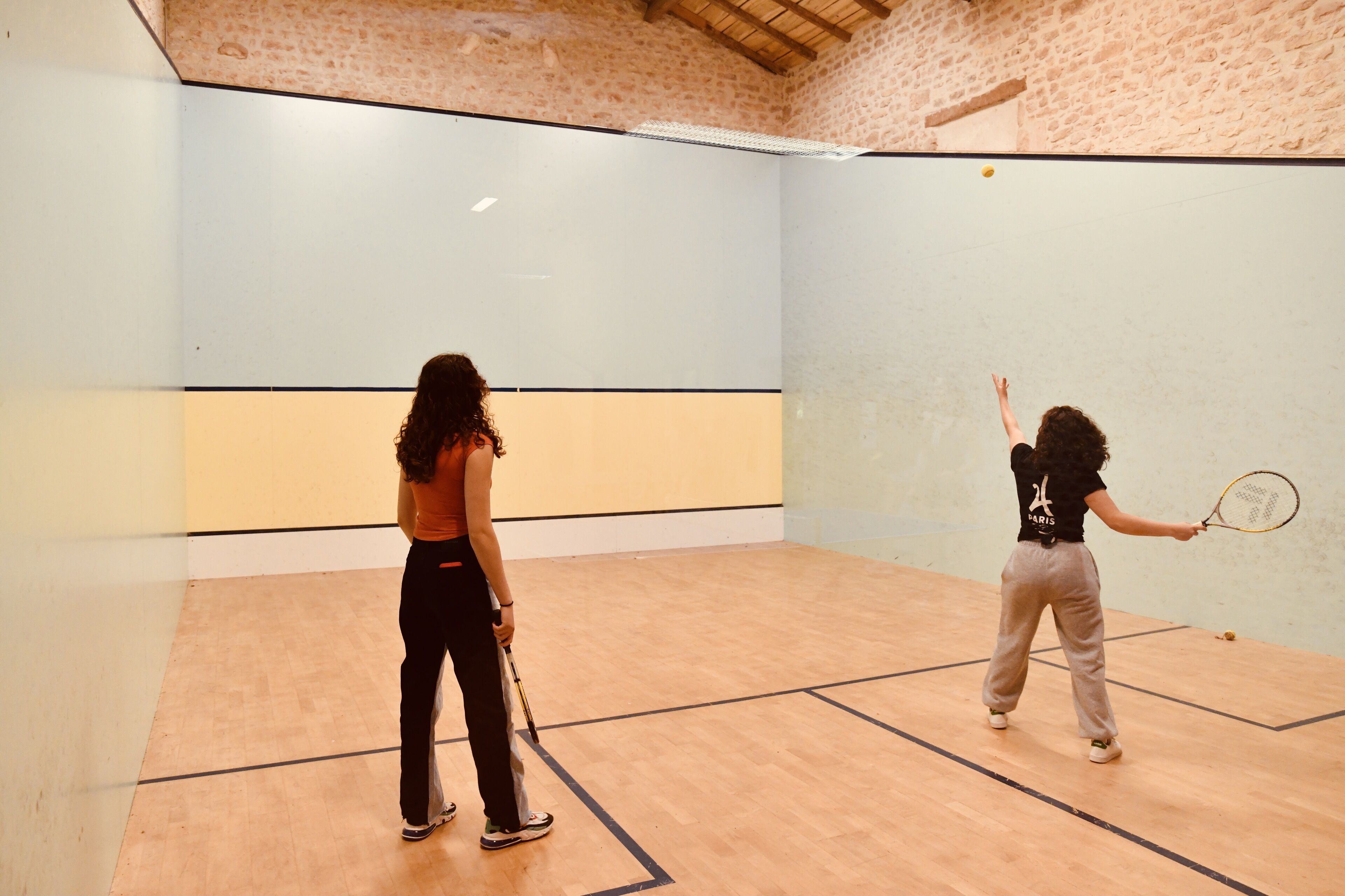Una cancha de squash con piso de madera y paredes azul claro.