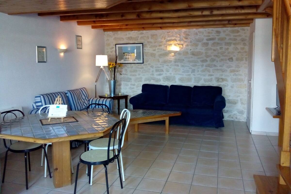 A dining area with a wooden table and chairs, a blue sofa, and a stone wall.