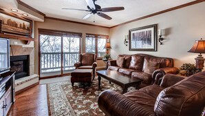 A living room with a fireplace, leather sofas, a coffee table, and a ceiling fan. - Premium Condo with Modern Finishings (Beaver Creek)
