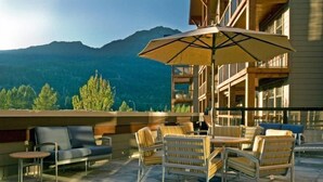 A terrace with outdoor seating, a large umbrella, and a mountain view. - Spacious + Modern Suite | Minutes from Whistler (Whistler)