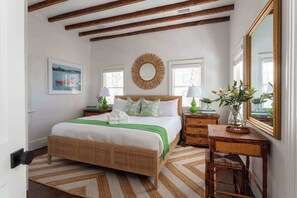 Un dormitorio con cama, mesitas de noche, un espejo y una ventana.