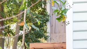 A wooden outdoor shower with a towel hanging on the door, surrounded by greenery. - Green Cottage – Private Casa Zoë Downtown Stay (Charleston)