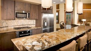 A modern kitchen with dark wooden cabinets, a stainless steel refrigerator, a built-in oven, and a granite countertop. - Alpine Condo + Fireplace, Balcony | Access to Spa (Breckenridge)
