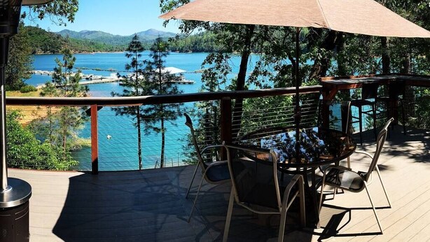 A deck with a table and chairs, overlooking a body of water and forested area. - Top Lakefront Oasis - Kayaks, Paddle Bd, - Shasta Lakeshore Retreat #2 (Lakehead)