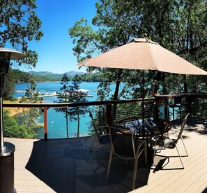 A deck with a table and chairs, overlooking a body of water and forested area. - Top Lakefront Oasis - Kayaks, Paddle Bd, - Shasta Lakeshore Retreat #2 (Lakehead)