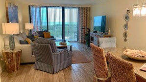 A spacious living room with a sofa, armchairs, and a dining table. - Stunning Beachfront Condo in Gated Community (Marco Island)