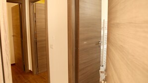 A hallway with wooden doors and a white wall. - Affittacamere Andolfi 24 (Pompei)