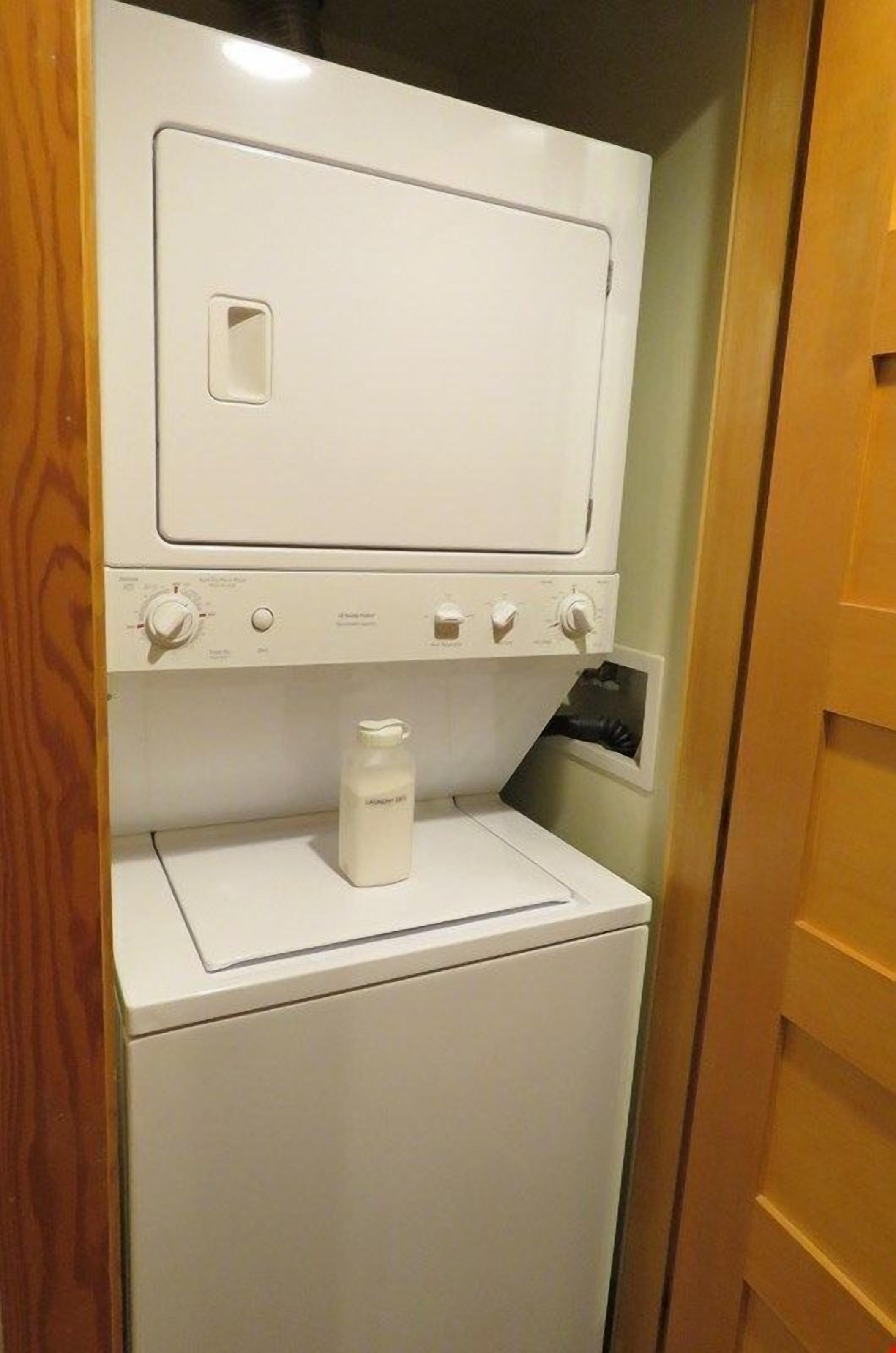 Een kleine, witte wasruimte met een ingebouwde wasmachine en droger.