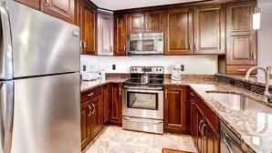Una cocina moderna con electrodomésticos de acero inoxidable, armarios de madera y encimera de granito.