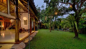 A spacious indoor area with a wooden structure, a seating area, and a well-maintained lawn. - Vibrant Soulful Bali Home for Short Term Rent (North Sanur)
