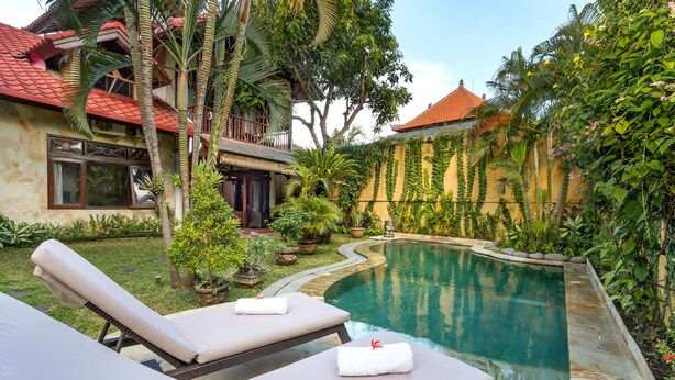 A pool area with lounge chairs and a stone-lined pool. - Vibrant Soulful Bali Home for Short Term Rent (North Sanur)