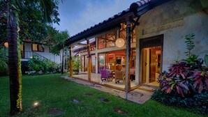A two-story building with a covered patio area, a staircase, and a well-maintained garden. - Vibrant Soulful Bali Home for Short Term Rent (North Sanur)