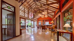 A spacious lobby with high ceilings, a polished floor, and a central seating area with chairs and a table. - Vibrant Soulful Bali Home for Short Term Rent (North Sanur)