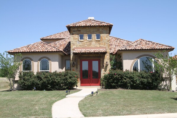 A two-story house with a red door, stone facade, and a tiled roof.
