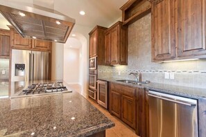 A modern kitchen with granite countertops, stainless steel appliances, and wooden cabinetry.