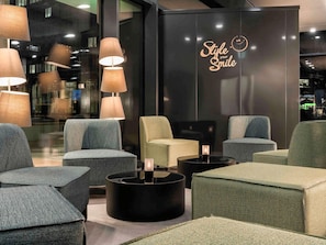 Un área de estar moderna con diversas opciones de asientos, incluyendo sofás y sillones, dispuestos alrededor de una mesa central.