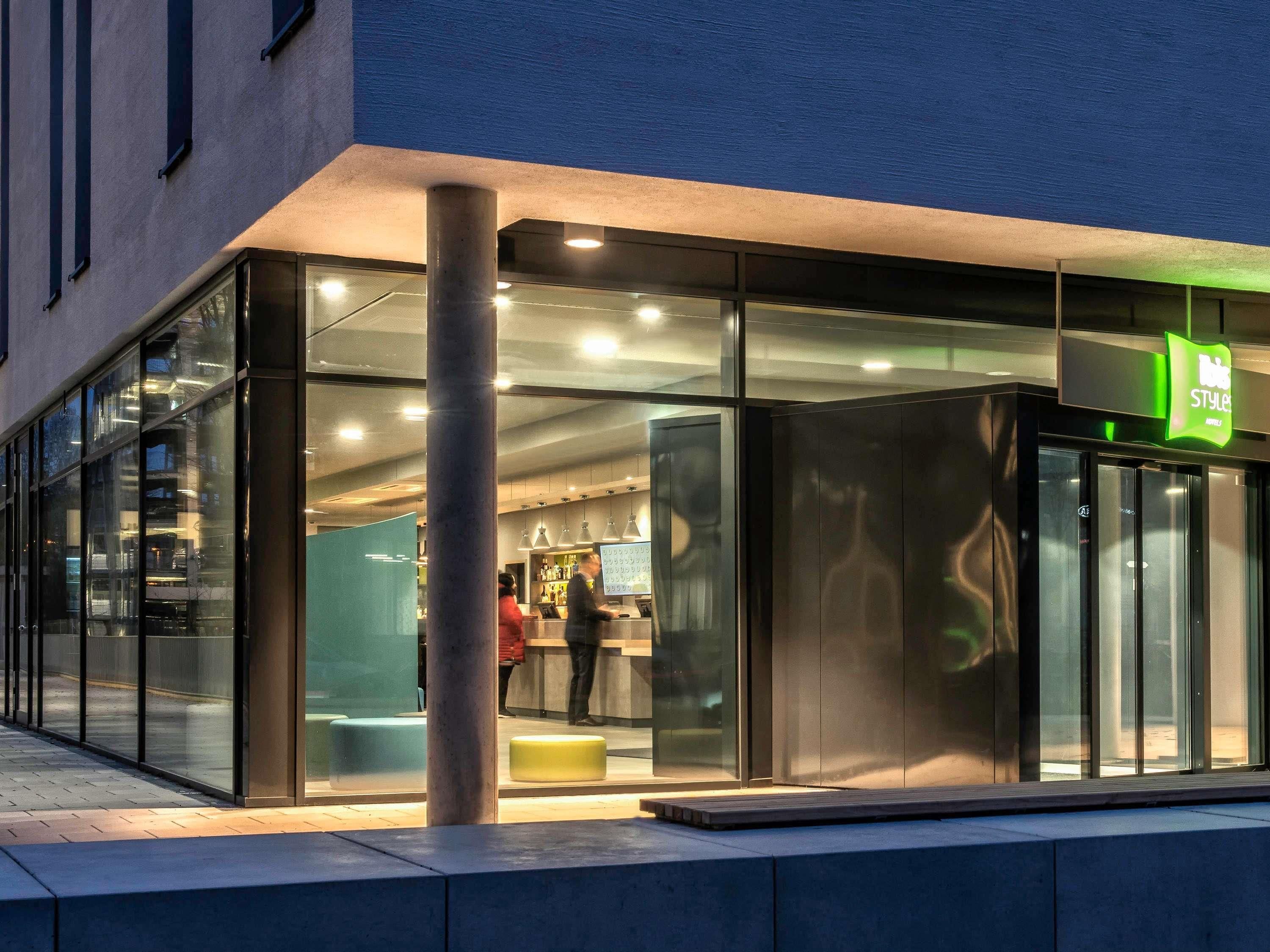 A modern building with a glass facade, a visible entrance, and a sign indicating a store or shop.