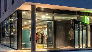 A modern building with a glass facade, a visible entrance, and a sign indicating a store or shop.