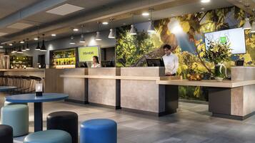A modern reception area with a bar, seating, and a digital display.