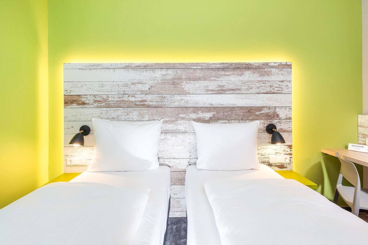 A room with two beds, a rustic wooden headboard, and a desk with a chair.