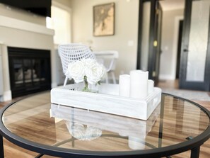 Une table ronde en verre sur laquelle repose un plateau blanc orné de roses blanches et de bougies.