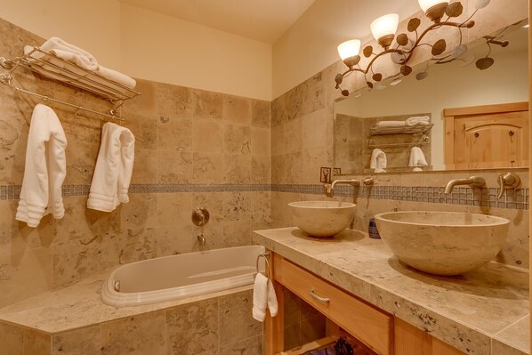 A bathroom with a bathtub, two sinks, and a towel rack.