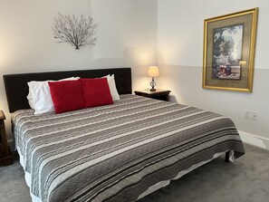 A neatly made bed with striped bedding, a black headboard, and a red pillow. - F4, Downtown, POOL, 2 king beds, 2 full bathrooms, free onsite parking! (St Augustine)