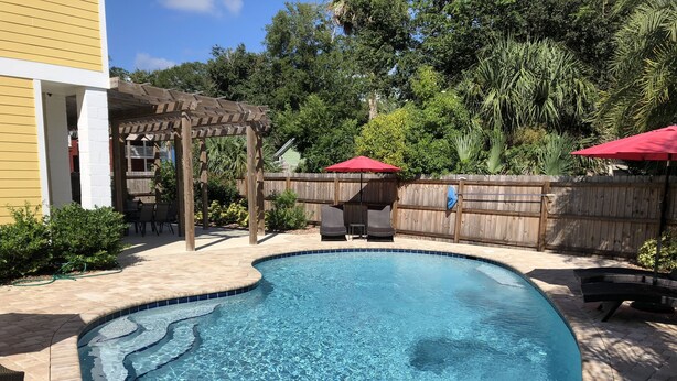 Una piscina con muelle de madera y pérgola.