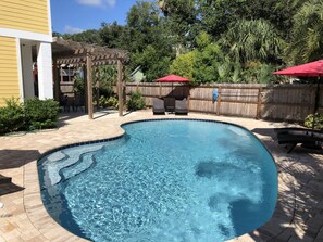 Ein Schwimmbad mit Holzterrasse und Pergola.
