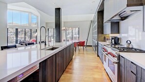 A modern kitchen with a large island, built-in oven, and a view of the outdoors. - Luxury Penthouse in Vail | Shared Hot Tub (Vail)