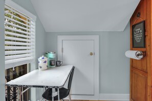 Ein Zimmer mit weißem Tisch, einer Tür und einem Fenster mit Jalousien.