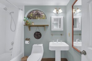 A bathroom with a shower, toilet, sink, and a mirror. - PERFECT COUPLES GET AWAY IN THE HEART OF DOWNTOWN BOERNE!! (Boerne)