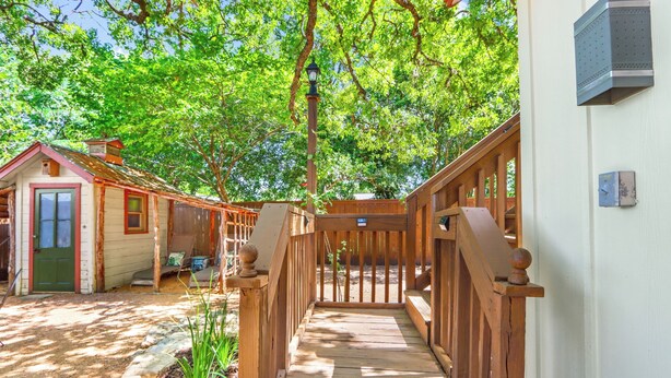 A wooden staircase leading to a covered porch with a view of a house and trees. - PERFECT COUPLES GET AWAY IN THE HEART OF DOWNTOWN BOERNE!! (Boerne)