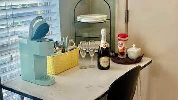 Un comptoir de cuisine avec une bouteille de Korbel Brut, une machine à café et un panier de fruits.