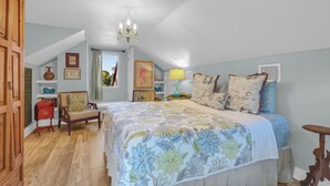 A bedroom with a large bed, a chandelier, a wooden wardrobe, and a window with curtains. - PERFECT COUPLES GET AWAY IN THE HEART OF DOWNTOWN BOERNE!! (Boerne)