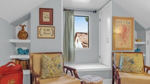 A room with two wooden chairs, a bench, a bookshelf, a red bag, and a window with a view of a building. - PERFECT COUPLES GET AWAY IN THE HEART OF DOWNTOWN BOERNE!! (Boerne)