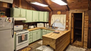 A kitchen with wooden cabinets, a stove, a microwave, and a wooden countertop.